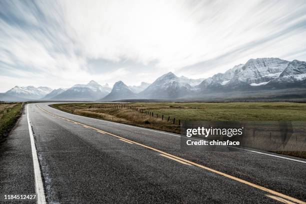 country road towards snow mountains against sky, canada - alerta stock pictures, royalty-free photos & images