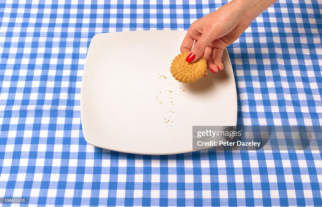 Woman taking last biscuit from plate