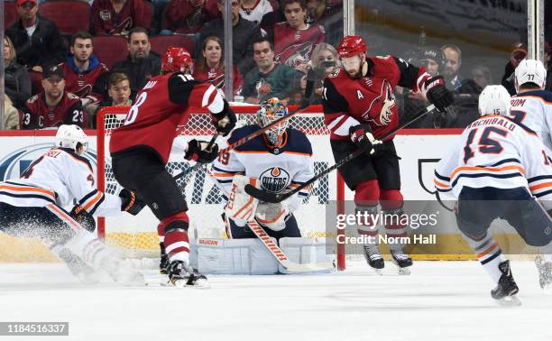 Goalie Mikko Koskinen of the Edmonton Oilers stops the puck on a re-direction attempt by Derek Stepan of the Arizona Coyotes as Kris Russell of the...