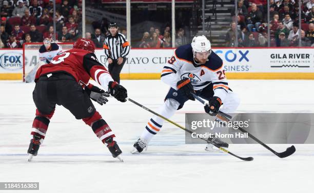 Leon Draisaitl of the Edmonton Oilers skates with the puck as Alex Goligoski of the Arizona Coyotes defends during the first period at Gila River...