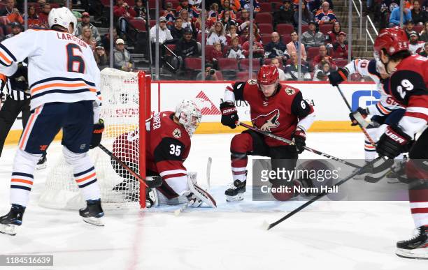 Goalie Darcy Kuemper of the Arizona Coyotes looks to cover a loose puck in front of Jakob Chychrun of the Coyotes as Adam Larsson of the Edmonton...