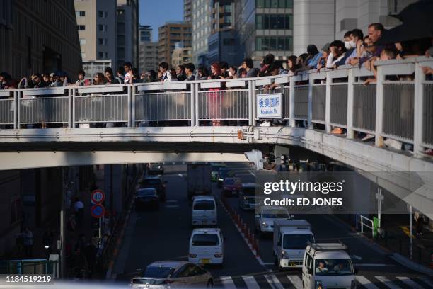 People on a bridge wait to see the motorcade of Pope Francis pass by on his way to the Tokyo Dome stadium for a holy mass, in Tokyo on November 25,...