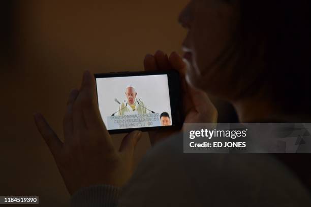 Woman watches live video on her mobile phone of Pope Francis leading a holy mass, outside the Tokyo Dome stadium in Tokyo on November 25, 2019.