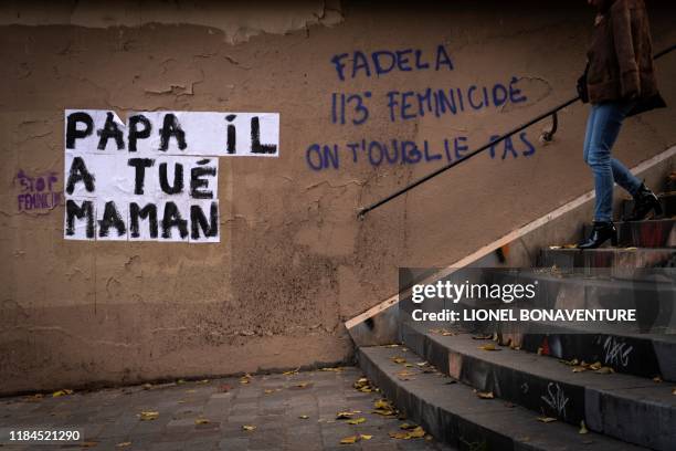 Women walks by a banner reading "Did daddy killed mummy " dedicated to the memory of women killed by a current or former partner, and against...