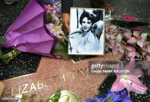 Fan places a photo beside flowers on Elizabeth Taylor's star at the Hollywood Walk of Fame in Hollywood, California on March 23, 2011. Legendary...