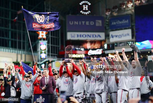 Manager Dave Martinez of the Washington Nationals hoists the Commissioners Trophy after defeating the Houston Astros 6-2 in Game Seven to win the...