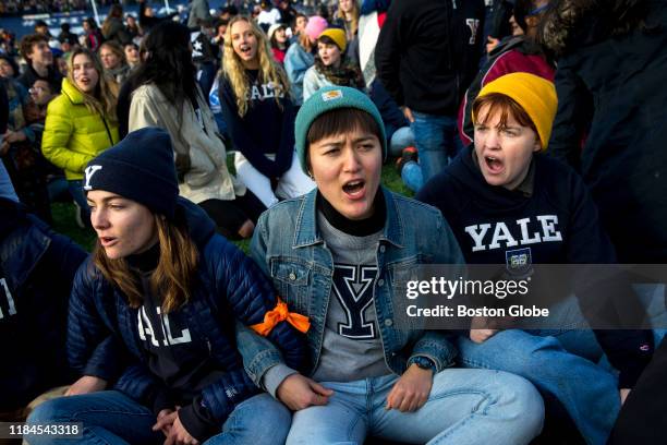 From left, Yale senior Nadia Grisaru, senior Sarah Adams and sophomore Lillian Burton protest during the halftime of the college football game...