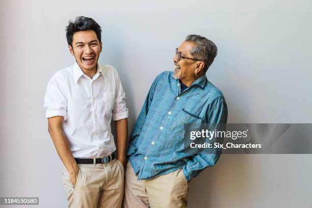 portret van aziatische senior vader en zijn volwassen zoon plezier samen en staande op grijze achtergronden - indian family portrait stockfoto's en -beelden