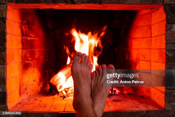 men's feet on the background of fire in the fireplace closeup - home furnace stock pictures, royalty-free photos & images