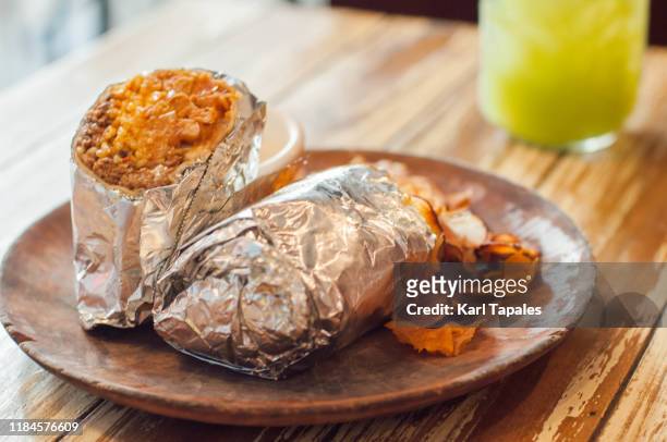 a close-up view of freshly made burrito on a wooden plate - burrito stockfoto's en -beelden