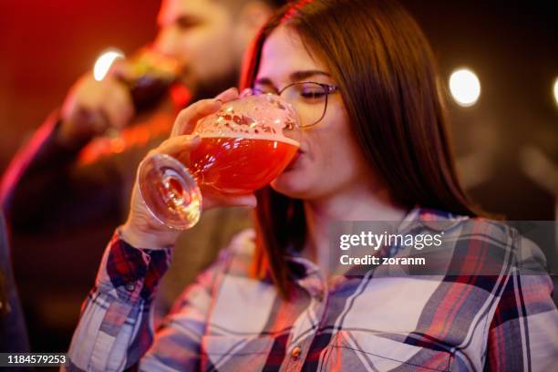 junge frau trinkt rotes bier mit vergnügen - real ale stock-fotos und bilder