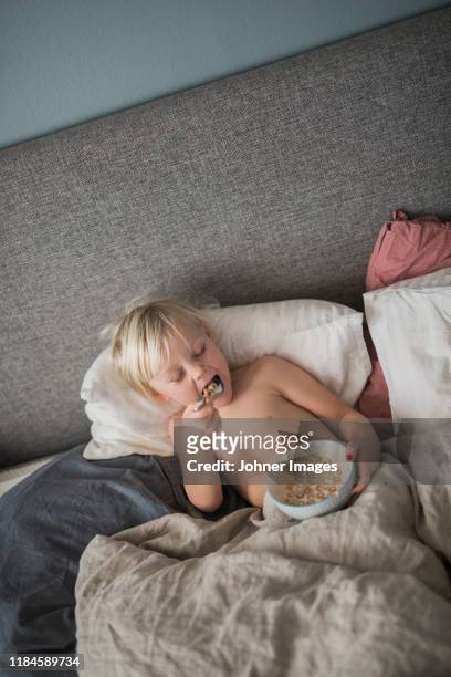 boy in bed eating cereals - child eating cereal stock pictures, royalty-free photos & images
