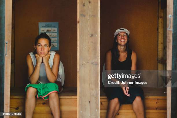 women in outhouse - woman sitting on toilet stock-fotos und bilder