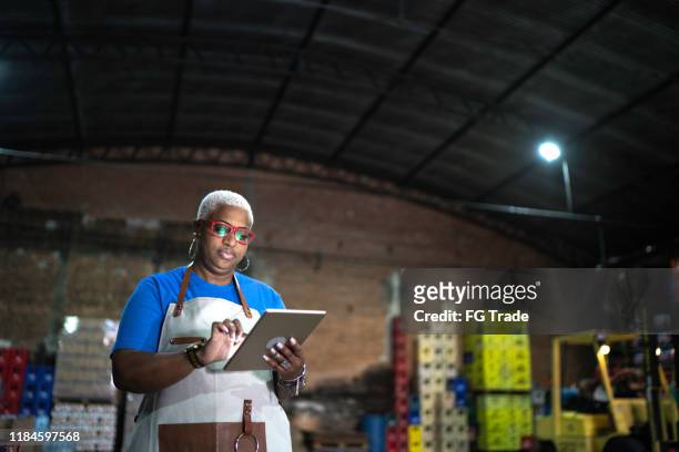 volwassen werknemer met behulp van digitale tablet at warehouse - market retail space stockfoto's en -beelden