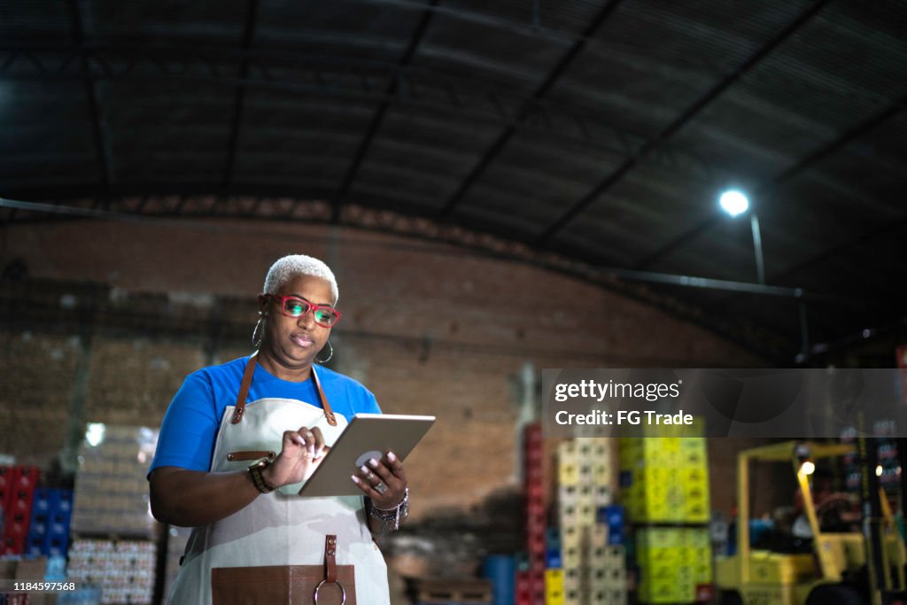 Mature employee using digital tablet at warehouse
