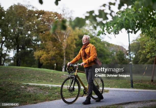 man pushing bicycle - adult riding bike through park stock pictures, royalty-free photos & images