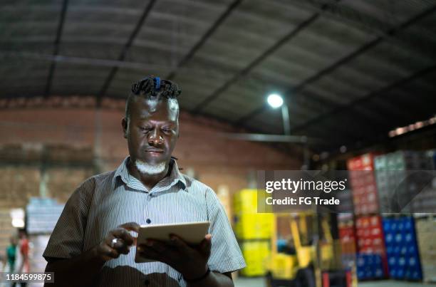 serious employee using digital tablet at warehouse - black stock trader stock pictures, royalty-free photos & images