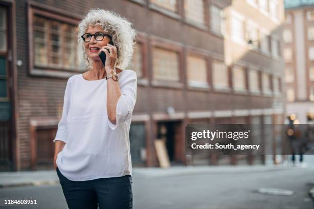woman talking on phone on the street - hands in pockets stock pictures, royalty-free photos & images