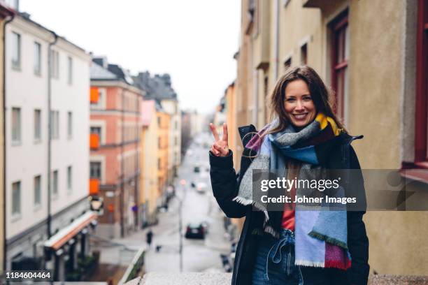 smiling woman looking at camera - victory sign stock-fotos und bilder