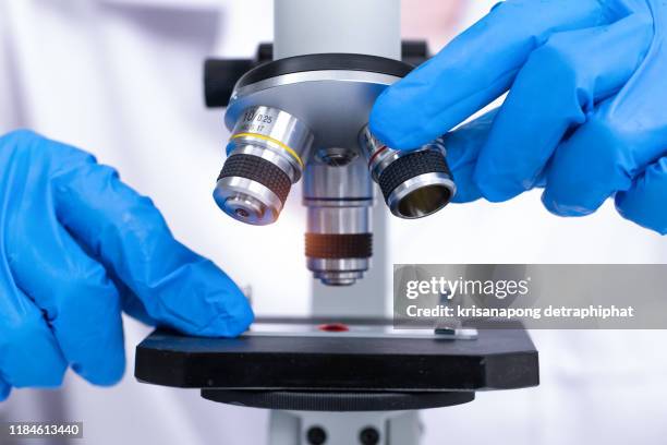 scientist looking through a microscope in a laboratory. young scientist doing some research. - life science stock pictures, royalty-free photos & images