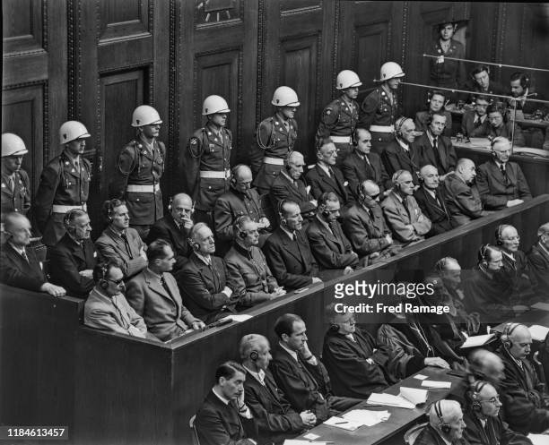 Nazi Defendants in the dock under guard in Room 600 at the Palace of Justice in Nuremberg during legal proceedings against leading Nazi figures for...