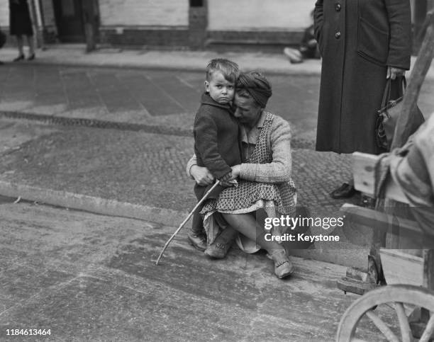 Homeless German refugee tries to console her son amidst the the destruction of post war Germany, Berlin, June 1945.