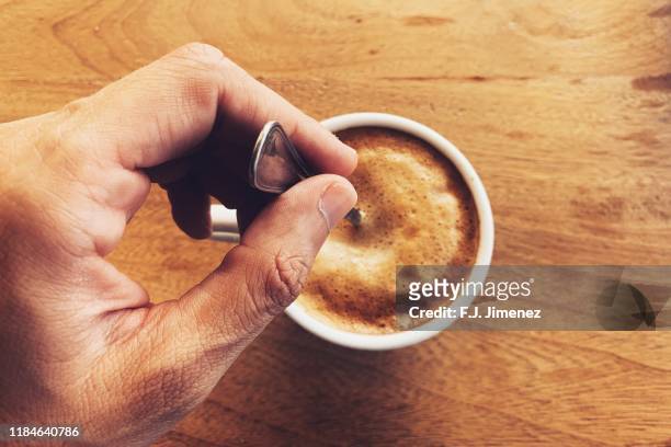 man's hand stirring coffee in cup - spoon in hand ストックフォトと画像