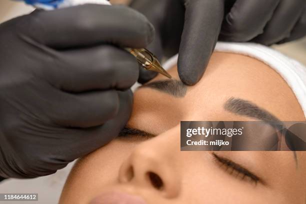 beautiful young woman receiving permanent make up - eyebrow tattooing stock pictures, royalty-free photos & images