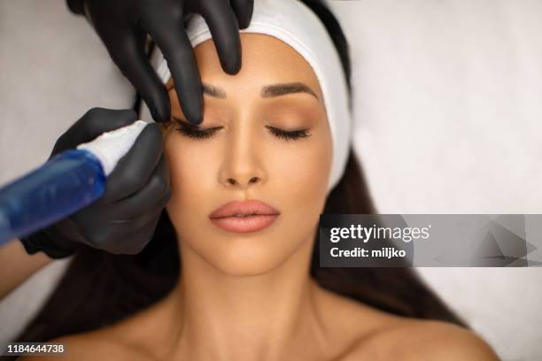 hermosa mujer joven recibiendo maquillaje permanente - eye liner fotografías e imágenes de stock