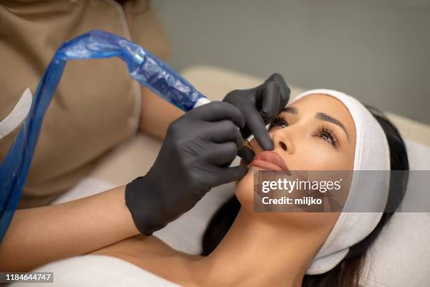 beautiful young woman receiving permanent make up - lip tattooing stock pictures, royalty-free photos & images