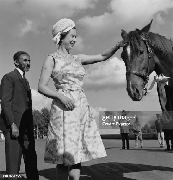 Queen Elizabeth II pats the head of a horse, watched by Emperor Haile Selassie during her royal tour of Ethiopia, February 1965.