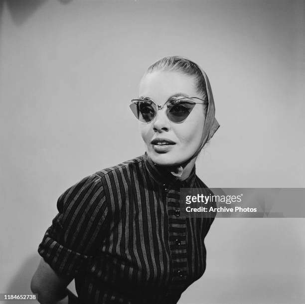 Young woman wearing cat's eye sunglasses with a headscarf, 1956.