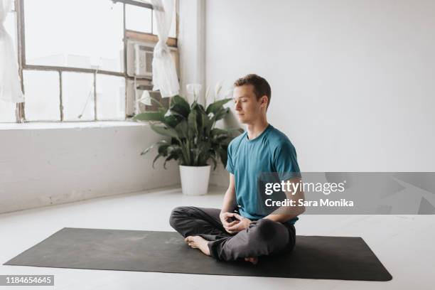 man sitting in lotus pose in yoga studio - yoga studio - fotografias e filmes do acervo
