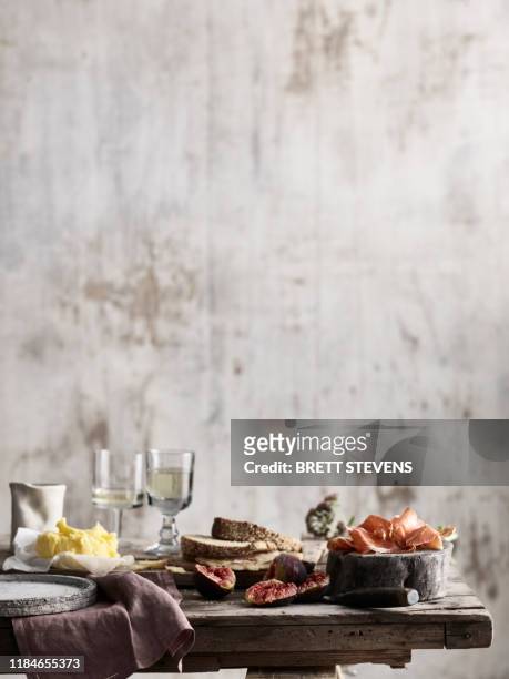 spread of bread, butter, figs and ham on table - still life foto e immagini stock