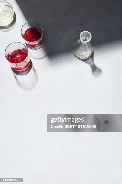 high key still life with glasses of red wine and white white wine on white table, overhead view - carafe stock pictures, royalty-free photos & images