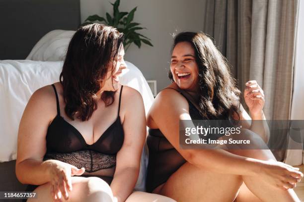 friends in lingerie laughing in bedroom - große brüste stock-fotos und bilder