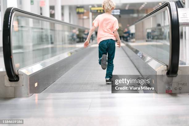 boy running on moving walkway in airport, full length rear view - moving walkway airport stock pictures, royalty-free photos & images