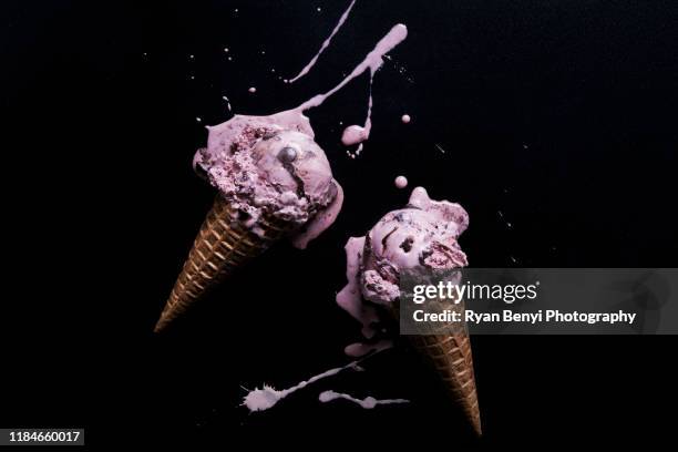 two chocolate chip raspberry ice-cream cones with melted splash against black background, overhead view - black raspberry ice cream stock pictures, royalty-free photos & images