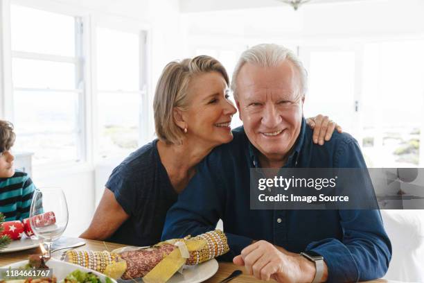 woman whispering into smiling man's ear at home party - child whispering stock-fotos und bilder