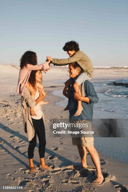 children piggyback fighting on parents at beach - girls wrestling stockfoto's en -beelden