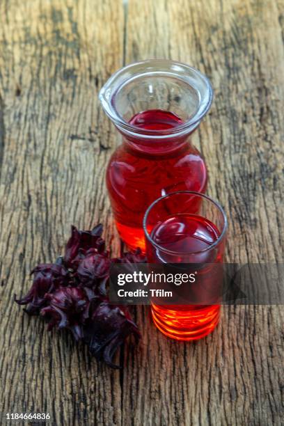 roselle juice in pitcher with glass and roselle fruit on wooden background - sauerampfer stock-fotos und bilder