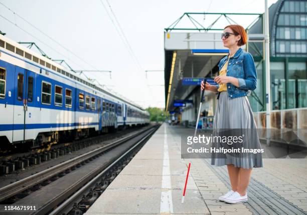 portrait of blind woman with white cane standing on train station outdoors in city. - blind woman stock pictures, royalty-free photos & images