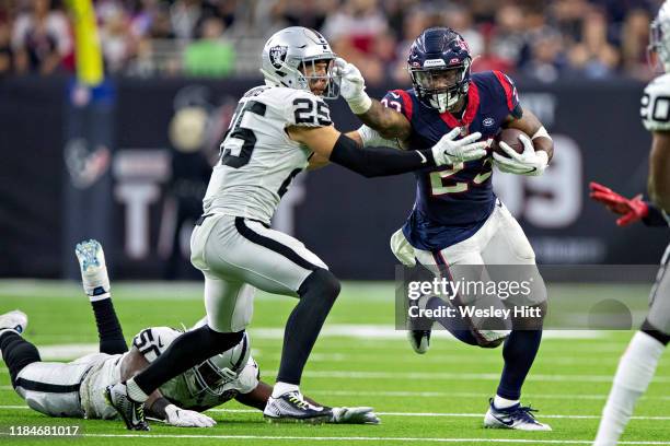 Carlos Hyde of the Houston Texans runs the ball and stiff arms Erik Harris of the Oakland Raiders at NRG Stadium on October 27, 2019 in Houston,...