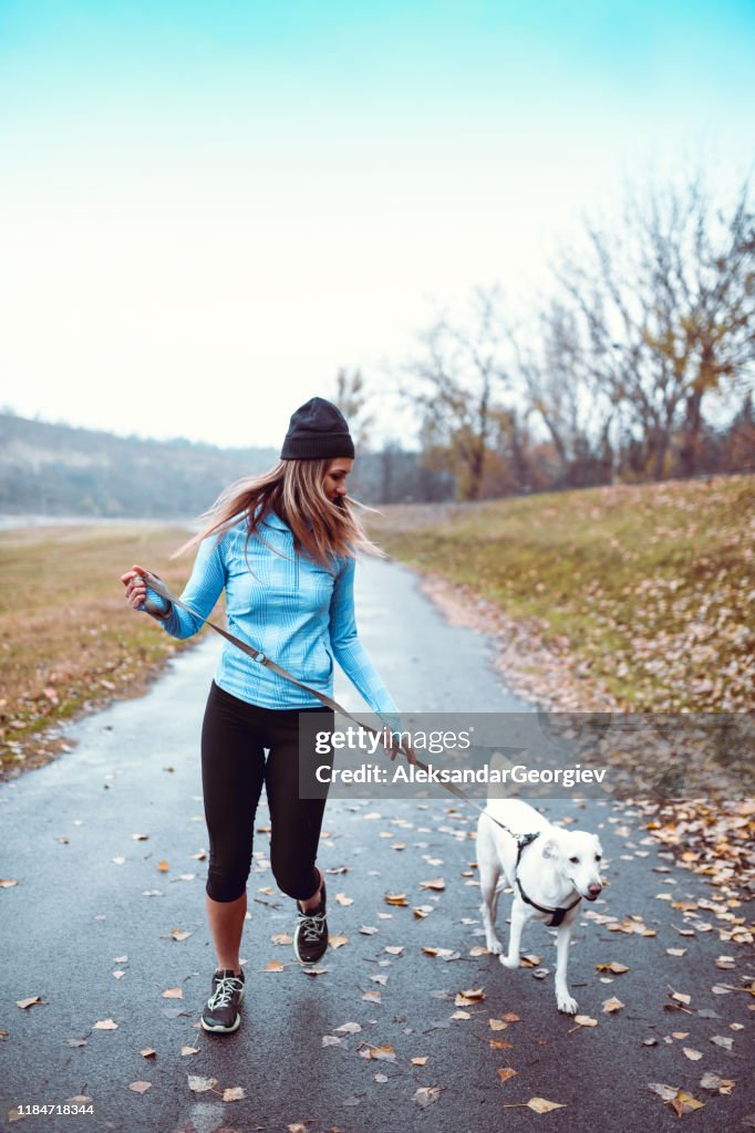 Female Athlete Running With Dog In Park