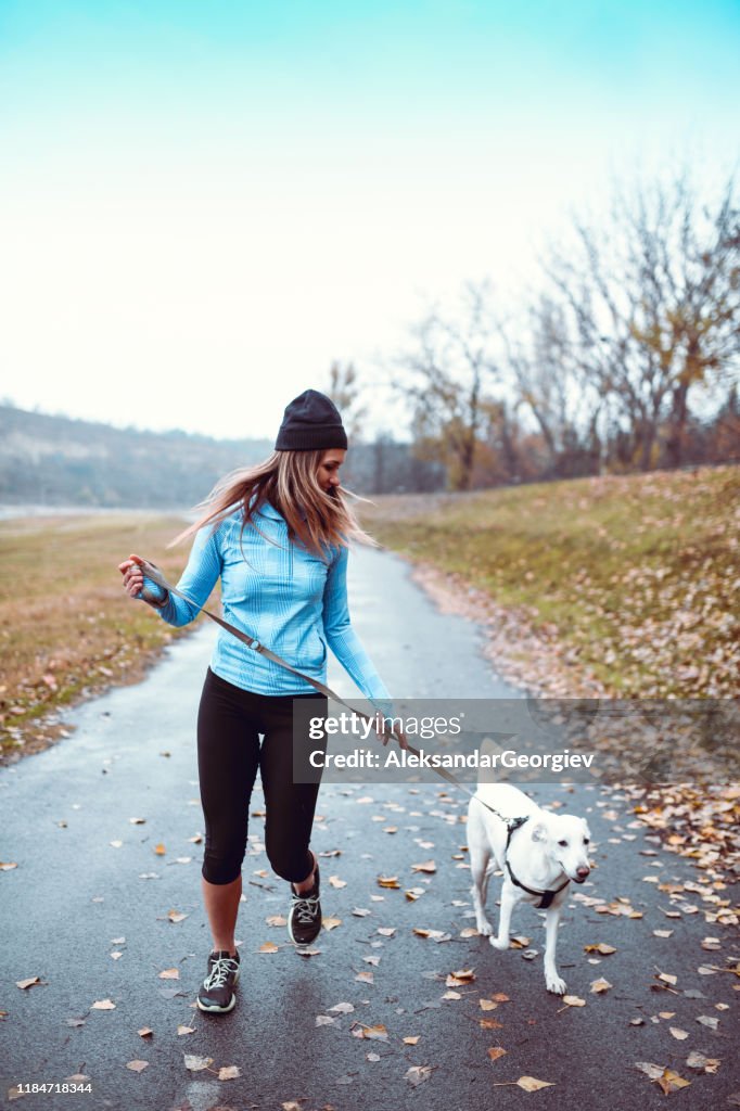 Kvinnlig idrottare som springer med hund i parken