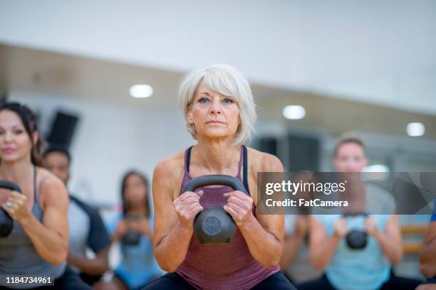 senior woman in fitness class using a kettlebell stock photo - skinny blonde stock pictures, royalty-free photos & images