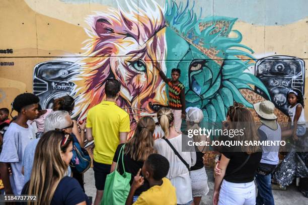 Girl explains a graffiti to tourists at the Comuna 13 neighborhood in Medellin, Colombia, on September 12, 2019. - With 25,000 monthly visits,...