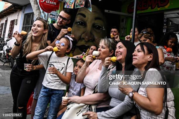 Tourists pose as they eat ice creams -known as "cremas"- at the Comuna 13 neighborhood in Medellin, Colombia, on September 15, 2019. With 25,000...