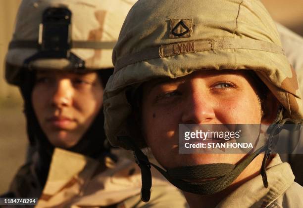 Army Pfc. Amanda Lynn and Spcl. Michelle Long , both of the 401 MP Company, 720 MP Battalion, listen to an early morning briefing, 14 February 2004,...