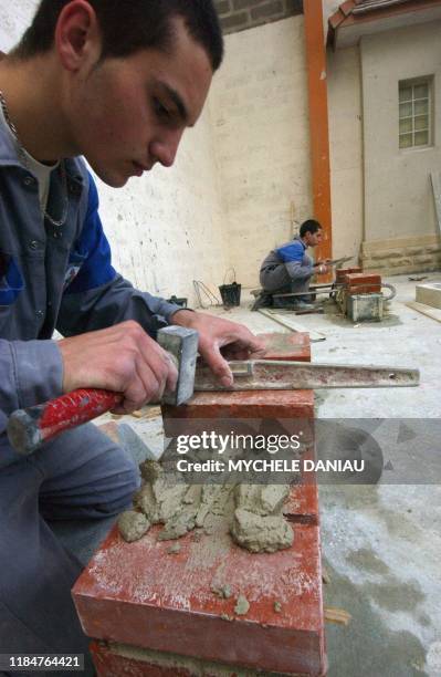 Des apprentis de première année du secteur maçonnerie apprennent les bases du métier pour réussir un mur en brique, le 24 novembre 2004 au centre...